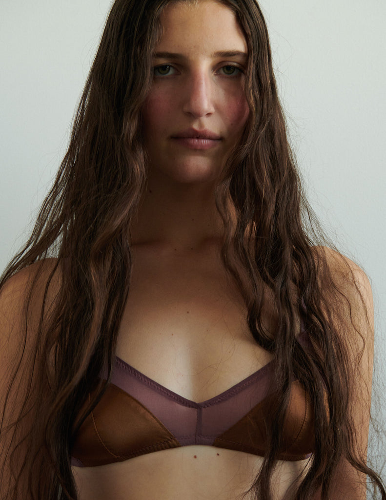 Woman wearing an Araks silk bralette in brulee brown against a plain background
