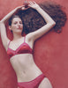 Woman in Araks silk red lingerie with matching panties lying on a red surface with an apple.