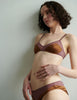 Woman wearing an Araks silk brown bralette and underwear set against a plain background