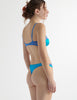 Side view of the woman in blue silk maya thong with beatrice bra