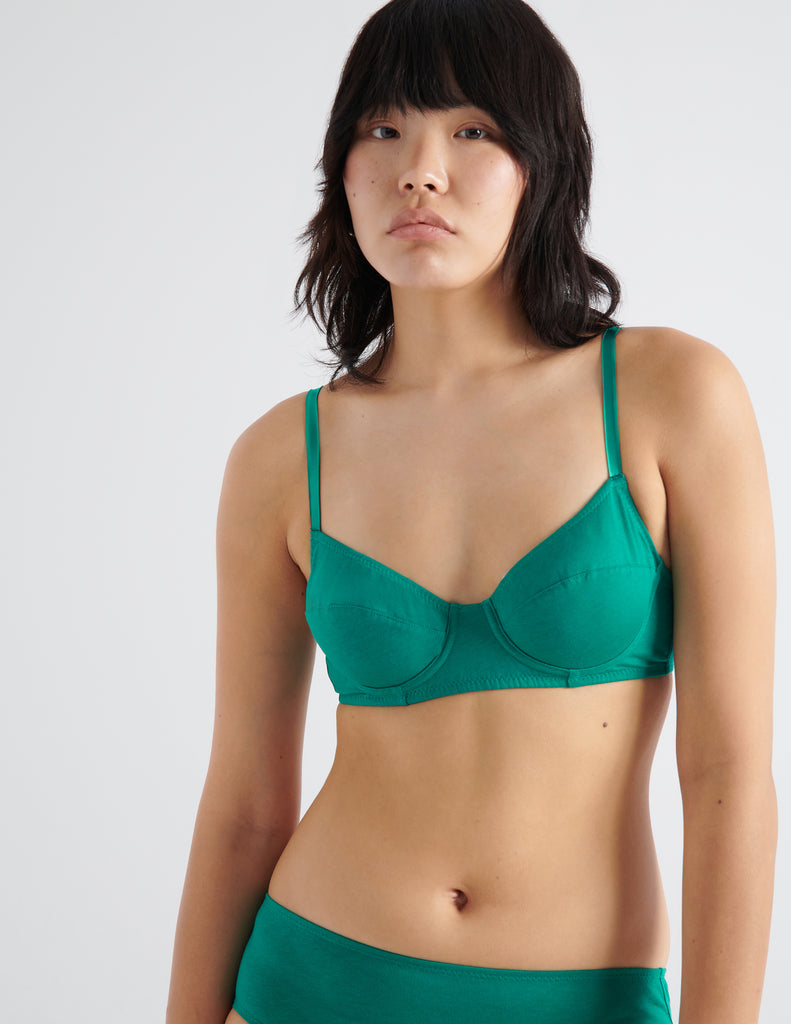 Close up front view image of model wearing green recycled organic cotton underwire bra and matching panties