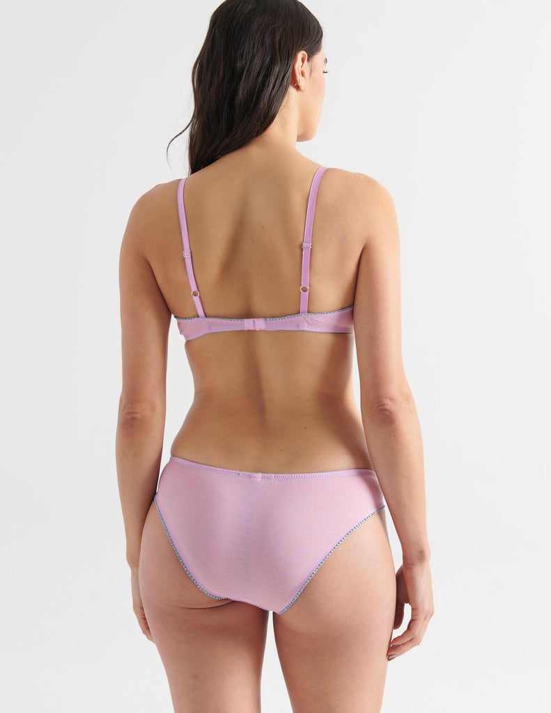Back view image of model wearing a pair of cotton crepe panties in a soft purple color with matching underwire bra. 