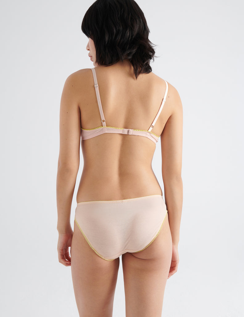 Back image of model wearing peach colored  cotton crepe underwire bra with matching panties. 