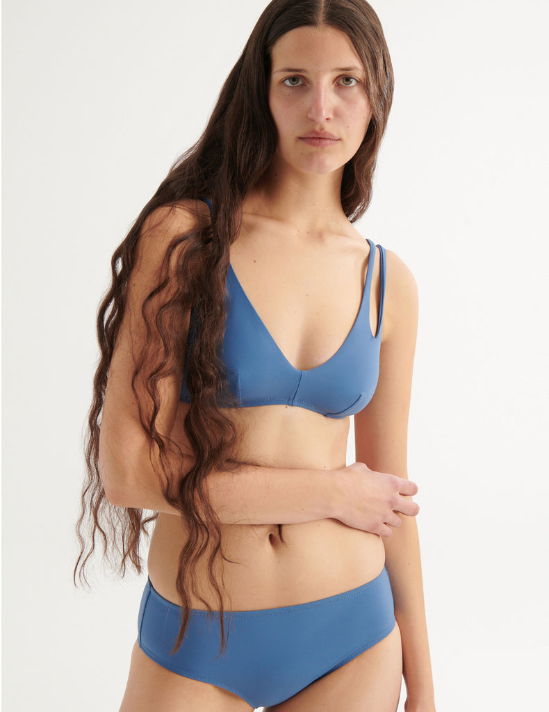 a model wearing elias bikini top and ezra hipster bikini bottom in fog blue 