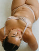 Woman wearing a beige gita bralette, in the shade bare, against a neutral background