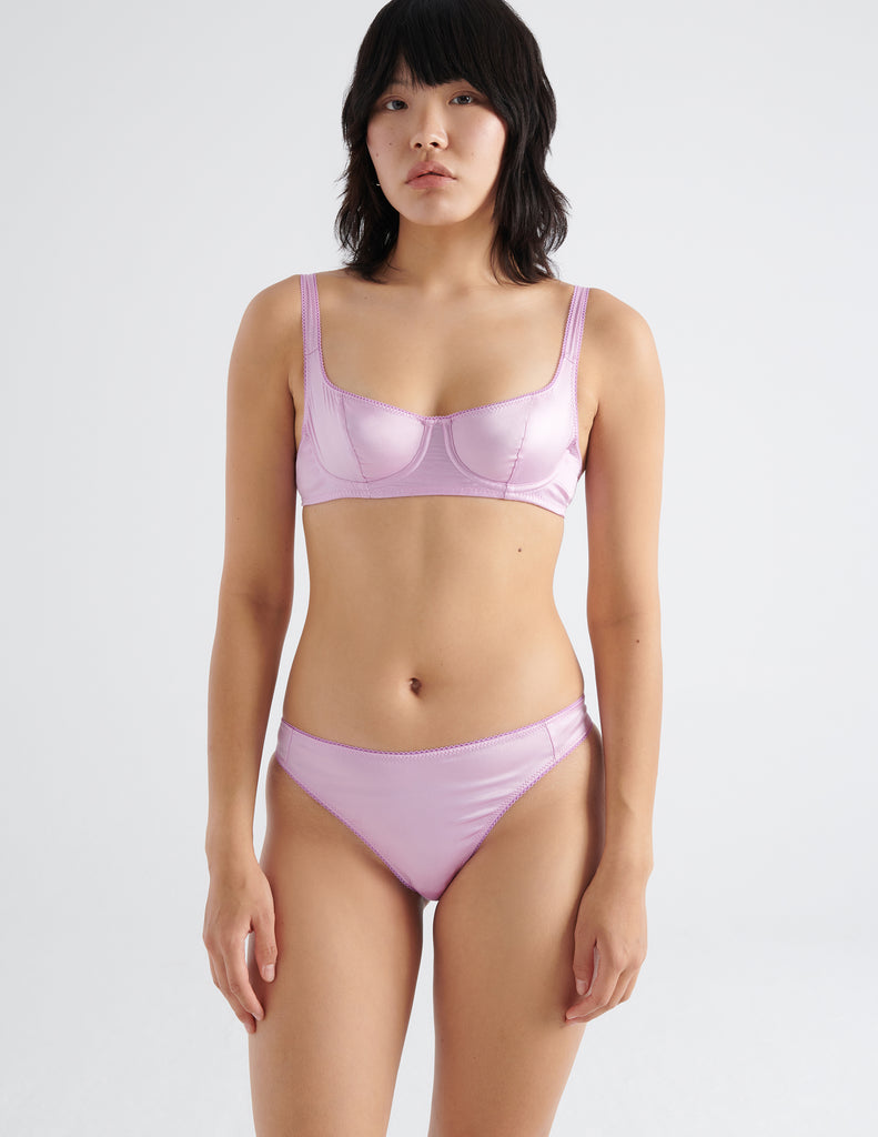Front view of model wearing pink silk panty with matching underwire bra. 