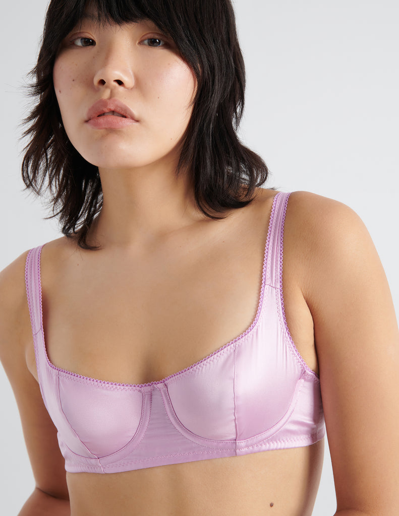 Detail front shot of model wearing pink silk underwire bra. 