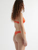 Back view of the woman wearing burst orange silk gita underwire bra with grier thong