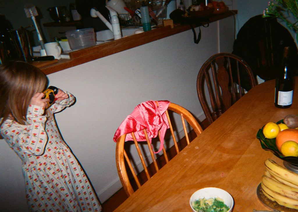 A girl taking a picture of a pink set on a chair.