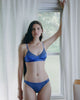 A model wearing a silk and cotton crepe bra and panty set, the willow bralette and harriet panty in storm blue