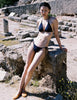 Model wearing the Araks Nelle bikini top and Nadia bikini bottoms in navy blue with red polka dots