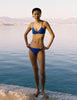 A model in the araks tessa bikini top and piper bikini bottom in azure