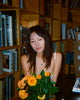 Woman holding a bouquet of flowers in a room with bookshelves.