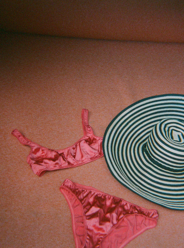 A pink bra and panty set with a stripe hat.