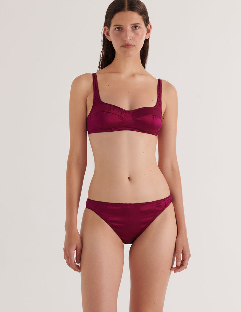 A model in the araks silk penelope bralette and gwyneth panty in cranberry red