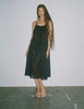 A model standing against a white backdrop, while wearing a rafaella slip dress in black. 