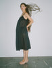 A model standing against a white backdrop, while wearing a rafaella slip dress in black. 