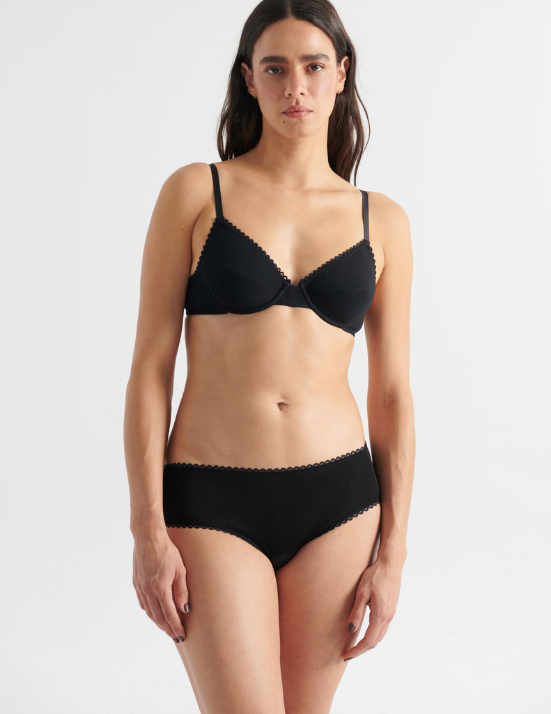 Front view image of model wearing black cotton underwire bra with black trim with matching hipster panty. 