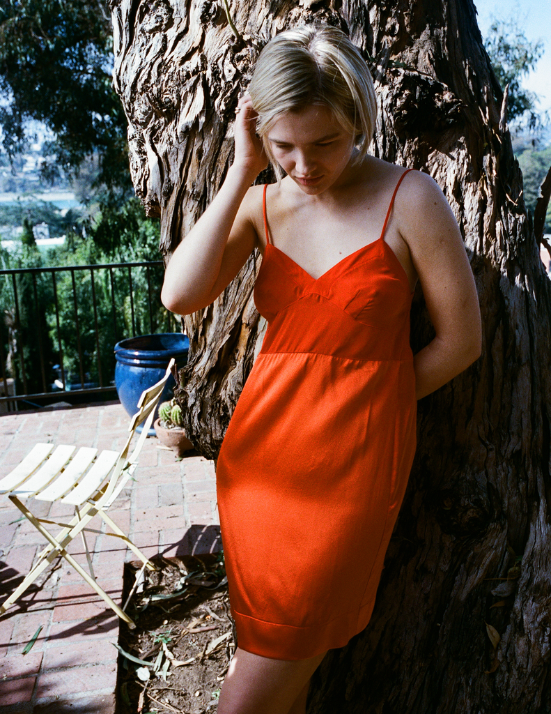 A model wearing a silk dress in orange color