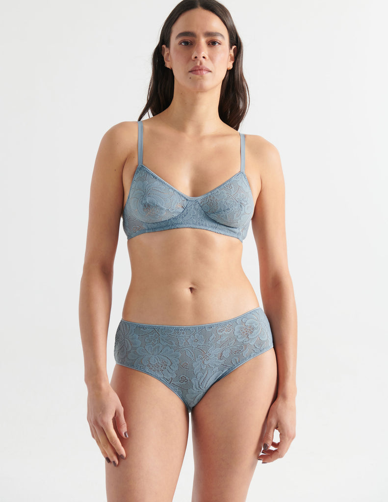 Front view image of model wearing grey lace hipster panties with matching bralette. 