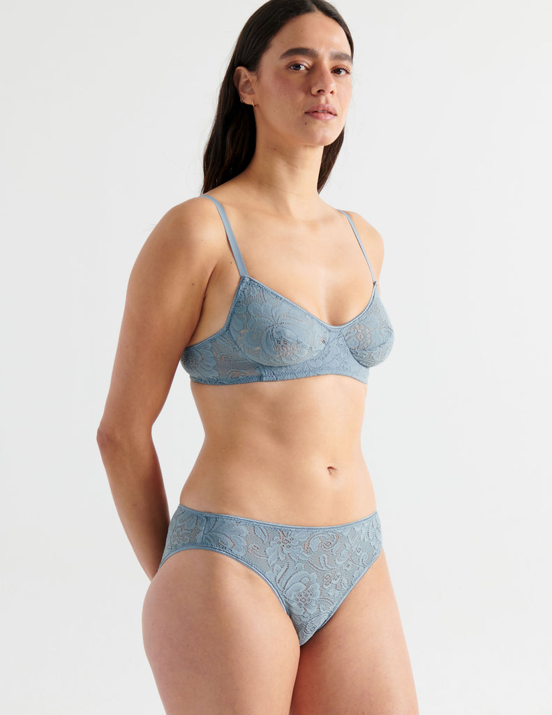 Three quarter view image of model wearing grey lace panties with matching bralette. 