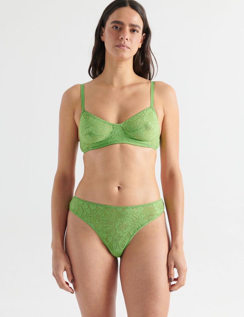 Front view image of model wearing green lace thong with matching bralette. 