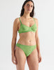 Three quarter view image of model wearing green lace bralette with matching thong. 