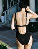 A back view of a model wearing the Araks Umi one piece in black. 