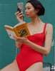 A model holding a book and camera while wearing the Araks scarlet red Umi on piece.