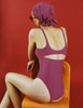 Woman wearing an Araks Usha purple swimsuit and matching headscarf sitting on an orange chair against a red background