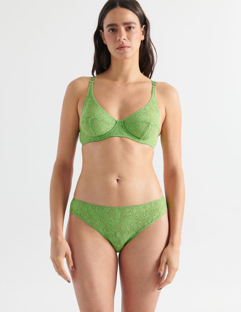 Front view image of model wearing green lace panties with matching underwire bra. 