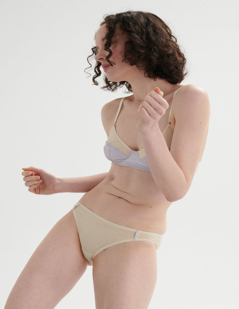 Woman wearing an Araks cotton cream bralette with a  panty against a white background