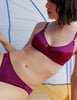Woman wearing a burgandy bralette with matching panty under a colorfull tent 