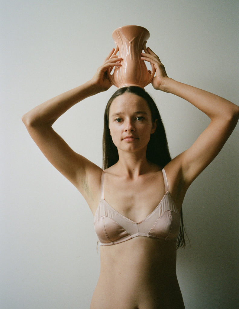 On model, editorial image of nude/pink bralette with a pot on her head 