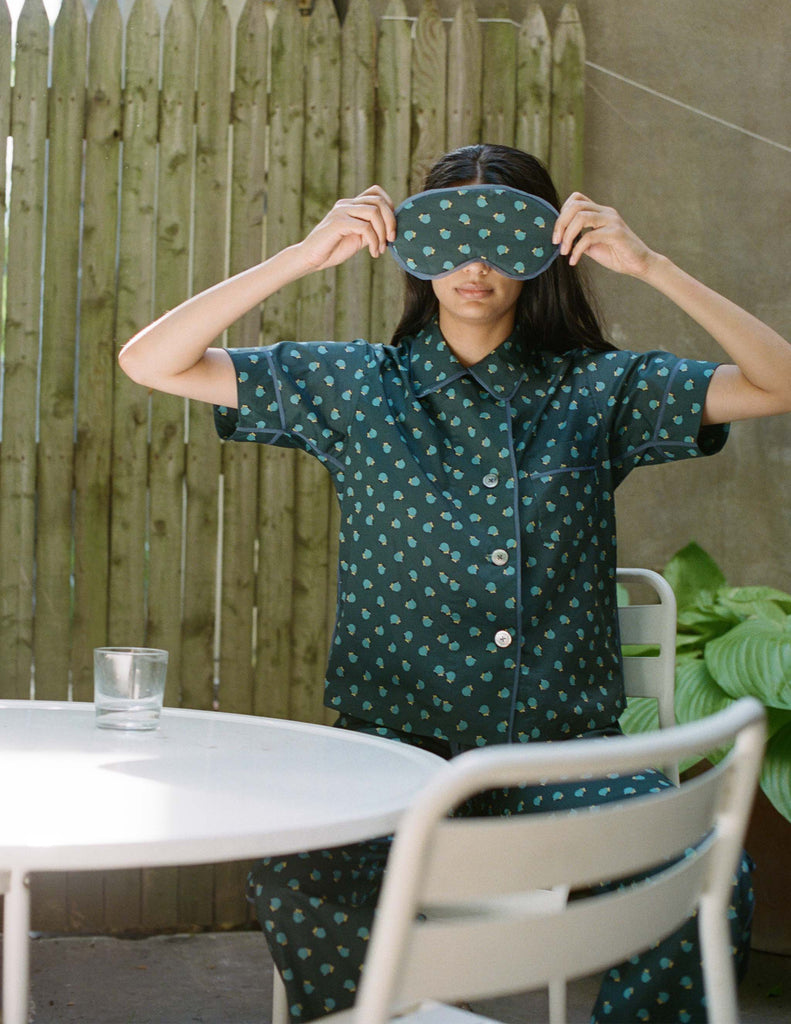 woman sitting at table wearing green print pajamas and matching eye mask by Araks