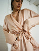 Woman wearing a short bare color silk robe by Araks