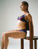 On model, editorial image or brown and blue bralette and panty, posed on a chair