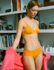 Woman in orange bra and panty with pink blanket