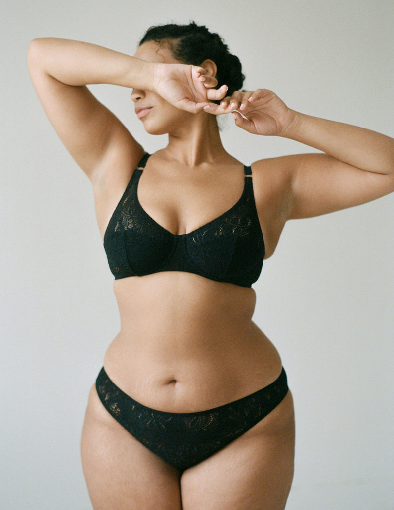 Front view of woman wearing black, lace underwire bra and matching  panty.