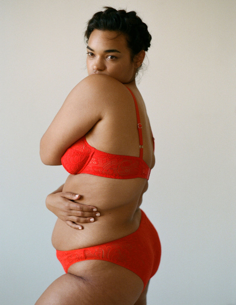 side view of woman wearing red lace underwire bra and matching panty