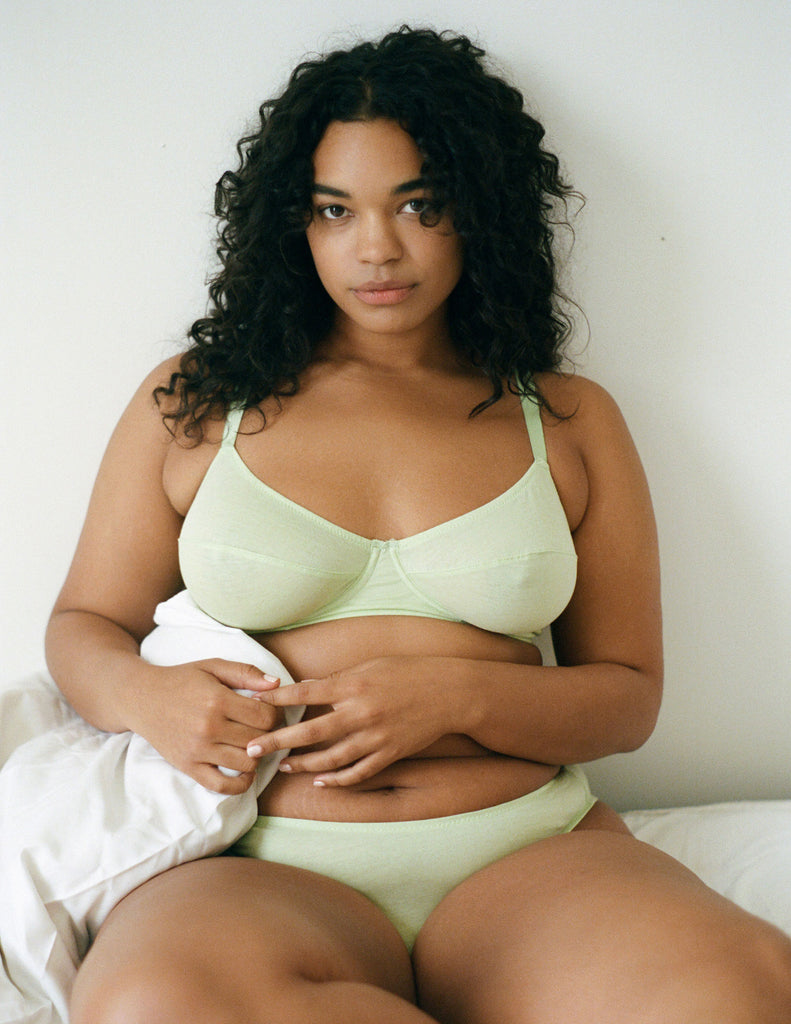 On model, editorial image of green underwire bra and panty