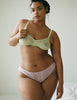 Woman wearing pale light green stretch lace soft cup bra with pale pink stretch lace panties