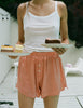 woman wearing white cotton tank  and peach colored silk boxers