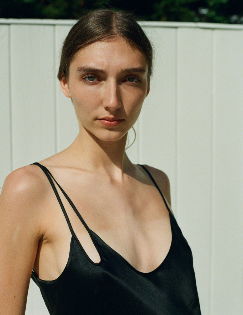 close up of woman wearing black silk slip with asymmetric straps