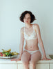 On model editorial image of white cotton bralette with white silk insets.