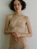 A woman wearing a beige cotton and silk bralette and matching panties by Araks