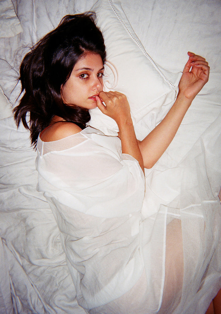 Woman on bed, wearing white long dress