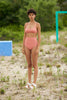 Woman in field wearing a peach pink wide scoop neck bikini top with matching high-waisted swim bottoms.