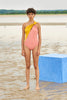 Woman wearing a yellow and peach asymmetrical one piece swimsuit with a split neckline and doubled one shoulder strap.