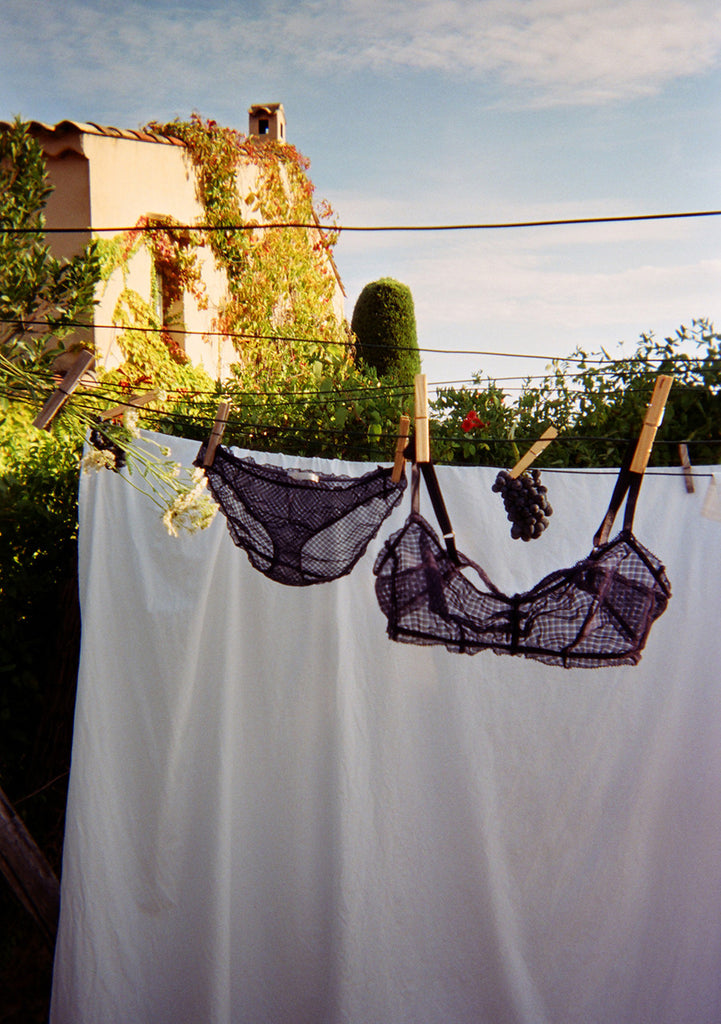 Black gingham mesh bralette and matching panty hung on clothesline outside. 